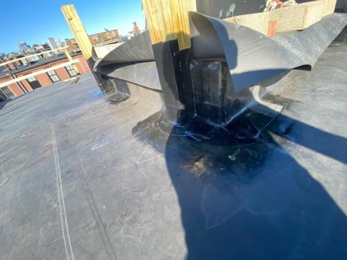 Installing rubberized roof system over tar and gravel roof system